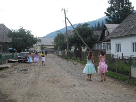 Hlavní ulice dědiny a děvčata jdoucí do kostela.
